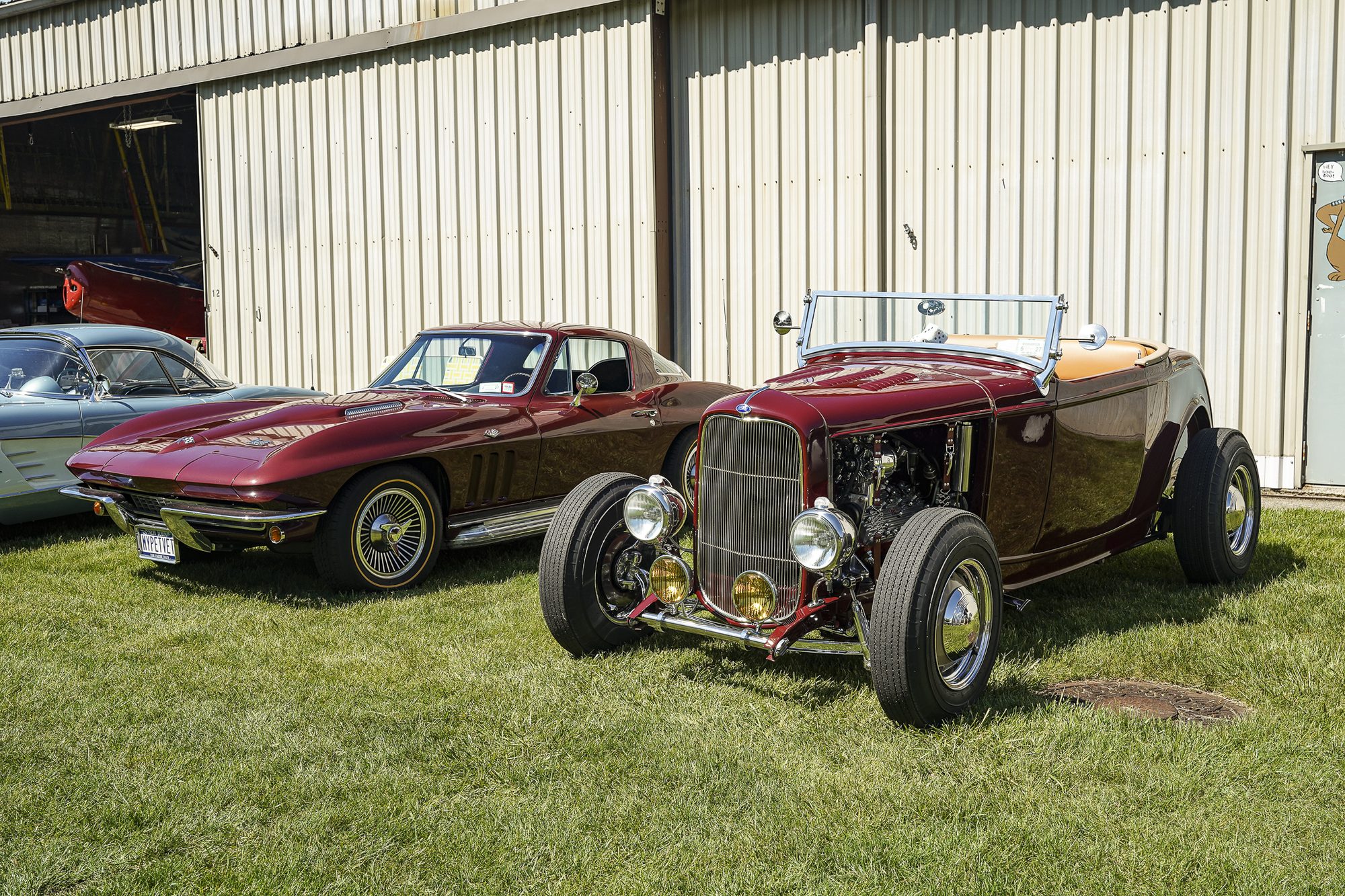 Maroon '32 Ford roadster hot rod parked beside a C2 Corvette Sting Ray